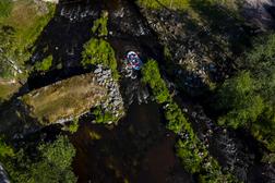 Ilmakuva joesta, jossa soutuvene kulkee kapeaa vesiv&auml;yl&auml;&auml; pitkin. Taustalla n&auml;kyy vihreit&auml; puita ja kivi&auml;.