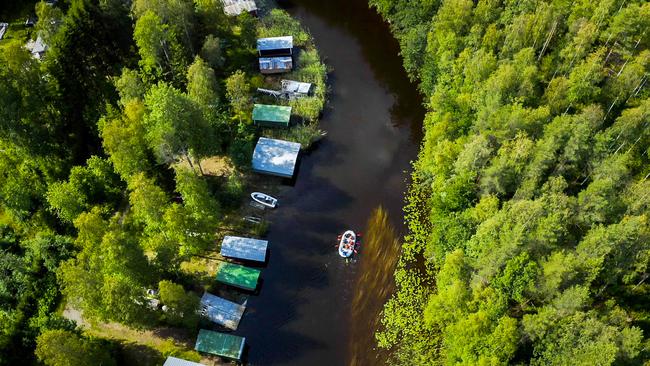 Ilmakuva kumilautasta Taipaleenjoella, jossa ryhmä meloo rauhallisesti metsäisen joen varrella, venevajoja näkyy joen rannassa.