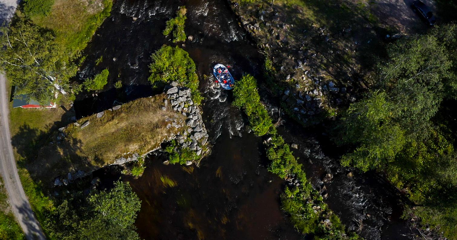 Ilmakuva joesta, jossa soutuvene kulkee kapeaa vesiv&auml;yl&auml;&auml; pitkin. Taustalla n&auml;kyy vihreit&auml; puita ja kivi&auml;.